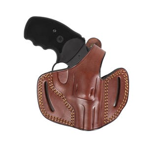 Peut inclure: Un étui en cuir marron avec un motif cousu et un revolver noir à l'intérieur.