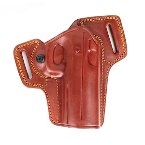 Könnte beinhalten: Eine braune Lederholster mit gelben Nähten. Die Holster hat ein geformtes Design und einen schwarzen Niet. Die Kanten sind mit gelbem Faden verstärkt. Die Holster ist für eine Handfeuerwaffe konzipiert.