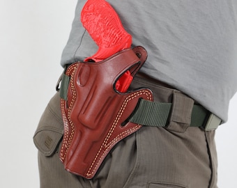 Könnte beinhalten: Ein braunes Lederholster mit einer roten Pistole darin. Das Holster ist an einem grünen Gürtel befestigt.