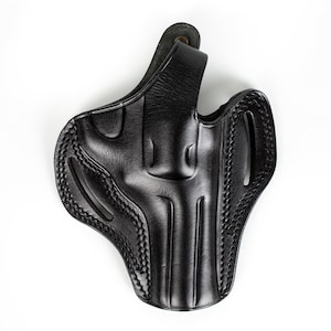 Könnte beinhalten: Ein schwarzes Lederholster mit einem genähten Design. Das Holster hat eine Gürtelschlaufe und eine Klappe zum Sichern einer Schusswaffe.