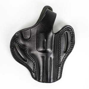 May include: Black leather holster with a stitched design. The holster has a belt loop and a trigger guard.