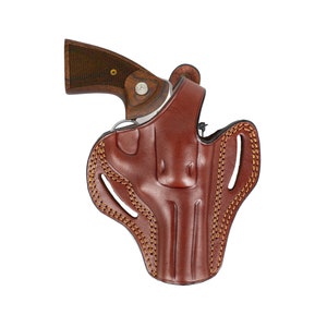 Peut inclure: Un étui en cuir marron avec un motif cousu et une arme à feu à l'intérieur.