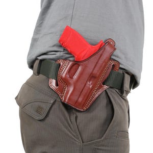 May include: A brown leather holster with a red gun inside. The holster is attached to a green belt.