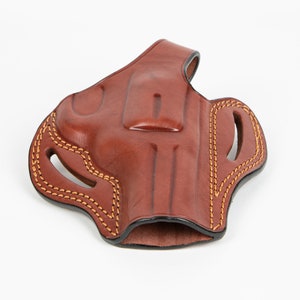 May include: A brown leather holster with a stitched design and a cut-out for a gun.