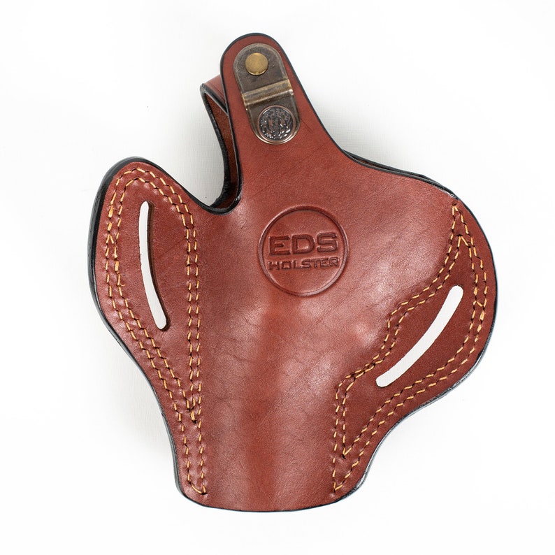 May include: Brown leather holster with a stitched design and a brass snap. The holster has the text "EDS HOLSTER" embossed on the front.
