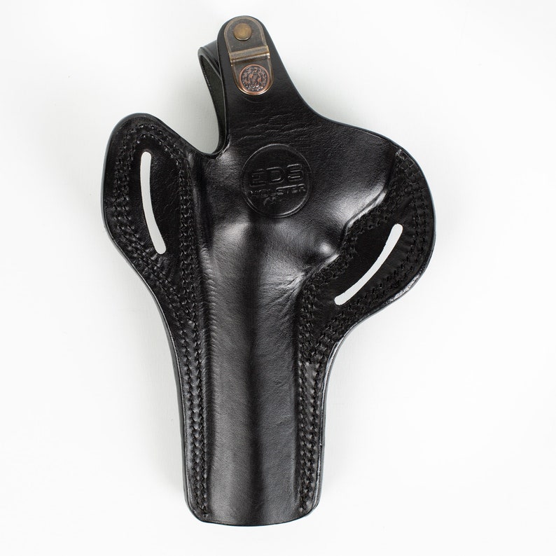 Pu&ograve; includere: Fondina in pelle nera con passante per cintura e dettagli di cucitura. La fondina ha un logo che dice "EDGE CUSTOM".