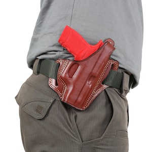 May include: A brown leather holster with a red gun inside. The holster is attached to a green belt.