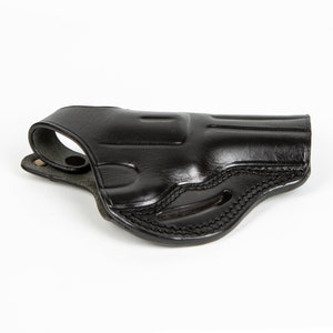 May include: A black leather holster for a handgun. The holster has a belt loop and a snap closure.