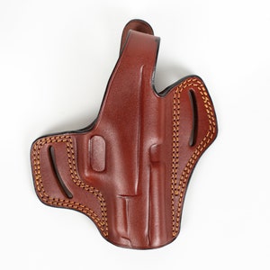 Op de afbeelding: Een bruine leren holster met stiksels. De holster heeft een klep die de bovenkant van het pistool bedekt.