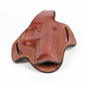 May include: A brown leather holster with a stitched design. The holster is open and empty.