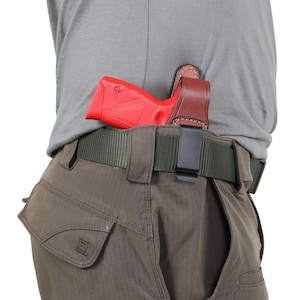 May include: A brown leather holster with a clip for a belt. A red handgun is inside the holster.