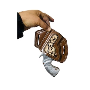 May include: A brown leather holster with a snakeskin pattern on the inside. The holster is designed to hold a small revolver.