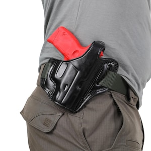 May include: A black leather holster with a red handgun inside. The holster is attached to a green belt.
