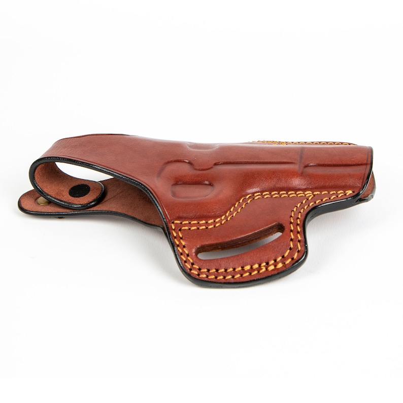 May include: A brown leather holster with a stitched design. The holster has a belt loop and a snap closure.