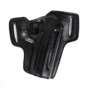 Op de afbeelding: Een zwart lederen holster met een gevormde vorm voor een vuurwapen, versterkte stiksels langs de randen en twee geïntegreerde riemsleuven aan de zijkanten. Een enkele zwarte metalen schroef is zichtbaar aan de linkerbovenkant van het holster.