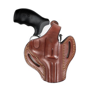 May include: A brown leather holster with a stitched design and a silver revolver inside.