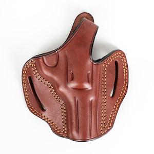 May include: A brown leather holster with tan stitching. The holster is shaped to fit a firearm, with cutouts and a belt loop. The leather has a polished finish.