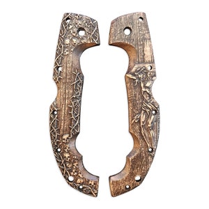 May include: Two wooden knife handle scales with intricate carvings. One scale features skulls and thorny vines, the other depicts a figure. Both are brown with drilled holes for attachment.