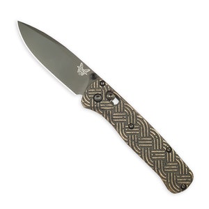 Könnte beinhalten: Ein schwarzes und goldenes Taschenmesser mit einem gemusterten Griff und einer teilweise geöffneten Klinge. Das Messer hat ein Schmetterlingslogo auf der Klinge.
