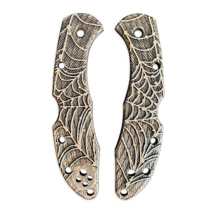 Può includere: Un paio di guance per coltelli marroni e nere con un design a ragnatela.