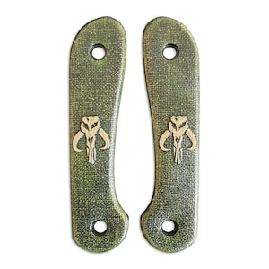 Può includere: Due guancette per manico di coltello verdi e marroni con finitura strutturata. Ogni guancetta presenta un emblema a teschio Mandaloriano color oro e un foro per il montaggio. Le guancette sono progettate per una costruzione di coltello personalizzata.