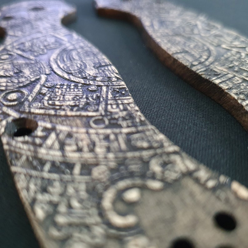 Puede incluir: Dos empu&ntilde;aduras de madera con intrincados tallados detallados. Las empu&ntilde;aduras son de color marr&oacute;n oscuro con un patr&oacute;n marr&oacute;n claro. Los tallados recuerdan s&iacute;mbolos o escrituras antiguas.