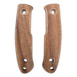 May include: Two brown wooden knife handle scales featuring a textured diamond-shaped checkering pattern across the surface. Each piece has three circular holes drilled through the wood, positioned at the top and bottom for mounting hardware.