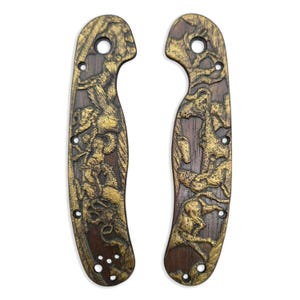 May include: Two intricately carved wooden knife scales with a detailed relief design. The scales are dark brown with gold-colored relief carvings depicting figures and animals. Each scale has pre-drilled holes for attachment.