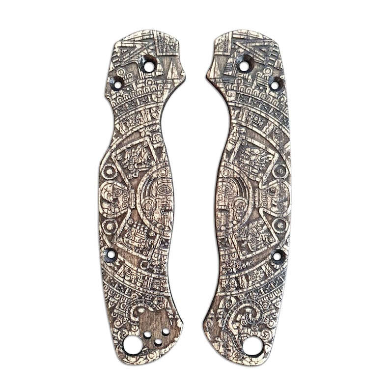 Puede incluir: Un par de cachas de cuchillo de madera marr&oacute;n con un dise&ntilde;o detallado del calendario azteca.