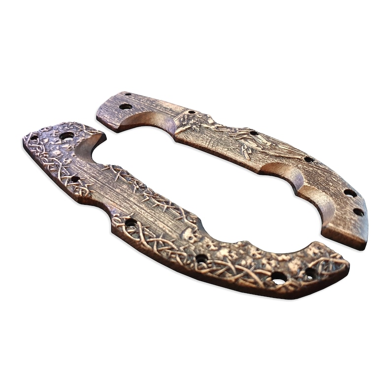 May include: Two bronze-colored knife handle scales with intricate Celtic knot and skull designs. The scales have a curved shape with multiple holes for attachment. One scale features a bird design.