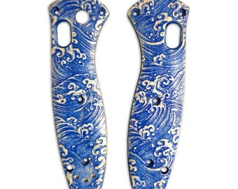 Könnte beinhalten: Zwei Messerschaftschalen mit einem blau-weißen Wellenmuster. Die Schalen sind gebogen und haben mehrere Löcher für Schrauben. Das Design erinnert an japanische Kunst mit einer detaillierten Darstellung von Meereswellen.