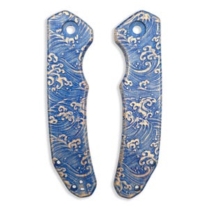 May include: Two blue and gold decorative knife scales with a wave pattern. The scales have a hole at the top and three smaller holes at the bottom. The wave design is in gold against a blue background.