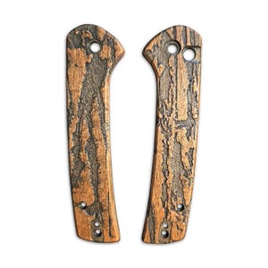 May include: A pair of brown and black wood knife scales with a wood grain pattern. The scales have three holes each for attaching to a knife handle.