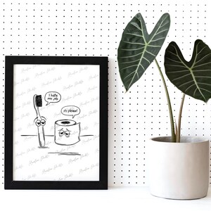 May include: A black framed print featuring a black and white cartoon illustration of a toothbrush and a roll of toilet paper with faces. The toothbrush has a speech bubble saying I hate my job and the toilet paper says oh please.