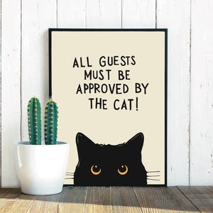 Puede incluir: Un cartel en blanco y negro con el texto "Todos los invitados deben ser aprobados por el gato!" con un gato negro asomándose desde abajo.