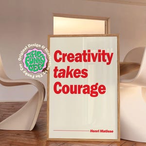 May include: A rectangular framed wall art print with a cream background and bold red text that reads Creativity takes Courage. Below the text is a thin red horizontal line followed by the name Henri Matisse. A circular logo is visible on the left.