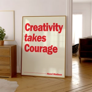 May include: A rectangular framed wall art piece featuring a cream-colored background with bold red text that reads Creativity takes Courage. The name Henri Matisse is printed in smaller red text at the bottom right with a horizontal line.