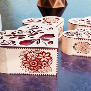 Pode incluir: Quatro caixas de madeira em forma de cora&ccedil;&atilde;o com desenhos florais intrincados e detalhes vermelhos. As caixas s&atilde;o feitas de madeira clara e t&ecirc;m um design delicado e intrincado.