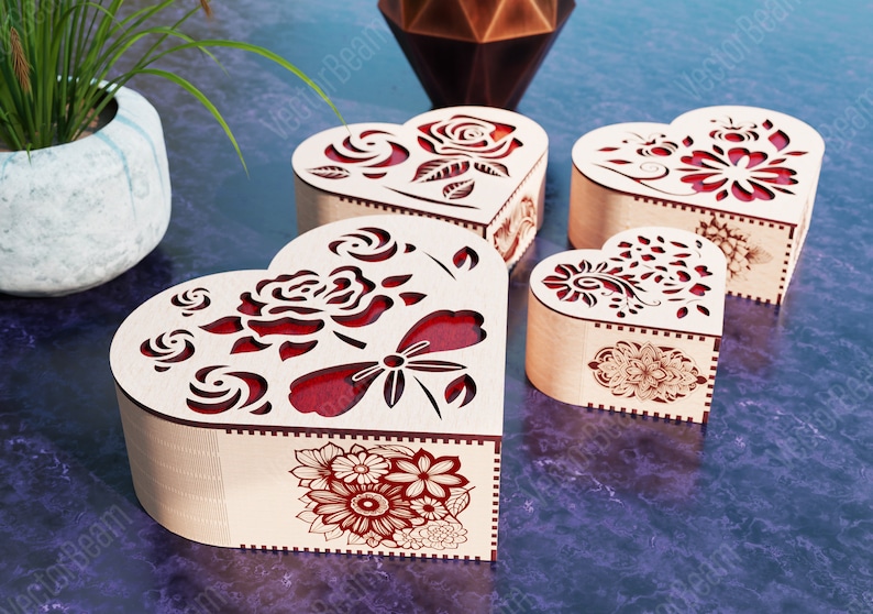 Pode incluir: Quatro caixas de madeira em forma de cora&ccedil;&atilde;o com intrincados desenhos florais cortados a laser. As caixas s&atilde;o feitas de madeira clara com detalhes vermelhos e apresentam diferentes padr&otilde;es florais, incluindo rosas, borboletas e outras flores.