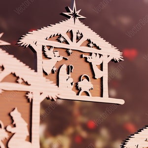 Puede incluir: Un adorno navide&ntilde;o de madera que representa la escena de la natividad. El adorno est&aacute; tallado con intrincados detalles, con un pesebre, una estrella y figuras de Mar&iacute;a, Jos&eacute; y el ni&ntilde;o Jes&uacute;s. El adorno est&aacute; pintado en un tono de madera natural.
