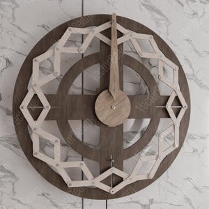 Puede incluir: Un reloj de madera marr&oacute;n con un dise&ntilde;o geom&eacute;trico blanco y plateado. El reloj tiene una aguja larga y fina que apunta a la hora.