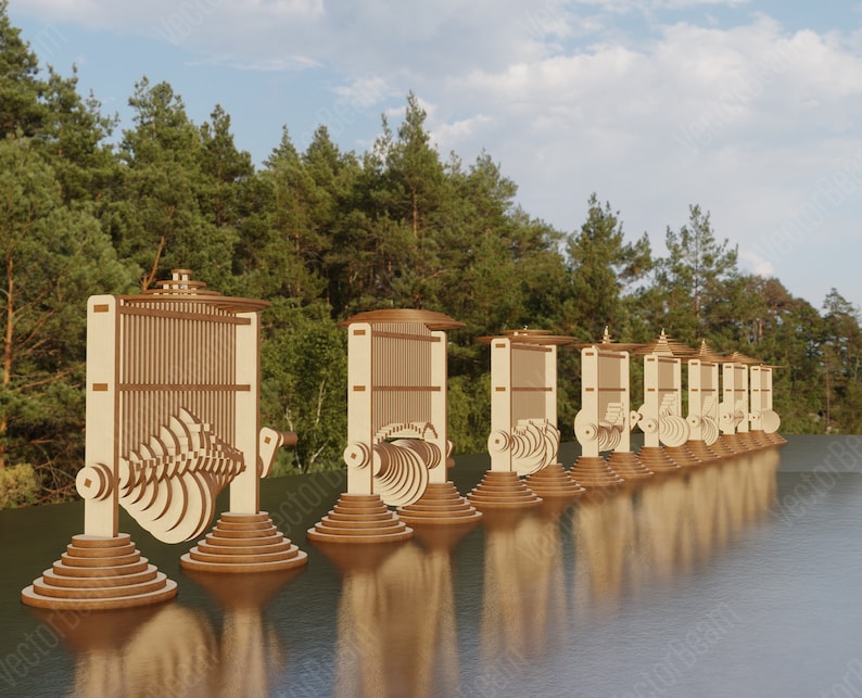 May include: A line of wooden kinetic sculptures with intricate moving parts, resembling a series of gears and wheels, are arranged in a line on a body of water. The sculptures are made of light brown wood and have a natural finish.