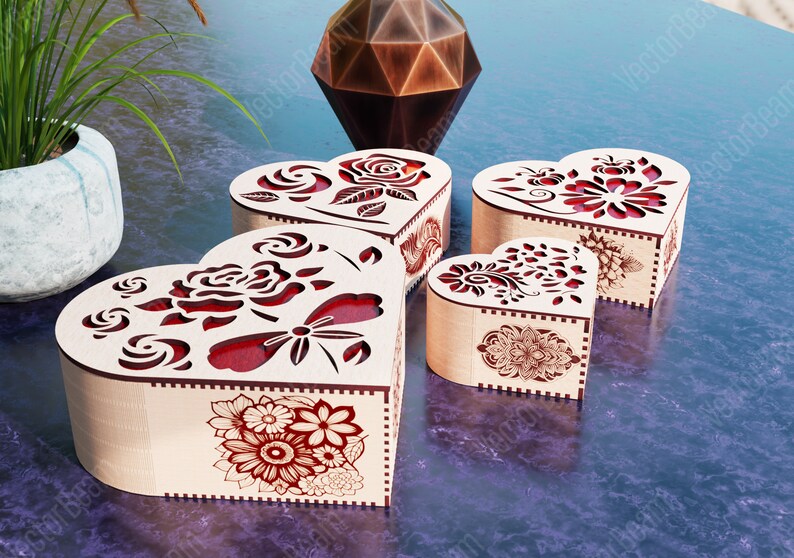 Pode incluir: Quatro caixas de madeira em forma de cora&ccedil;&atilde;o com intrincados desenhos florais e detalhes vermelhos. As caixas est&atilde;o dispostas em uma fileira sobre uma superf&iacute;cie roxa.