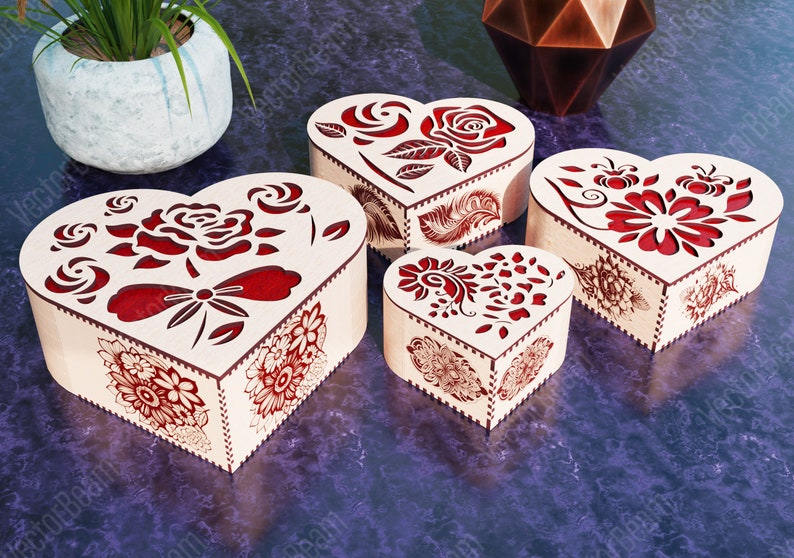 Pode incluir: Quatro caixas de madeira em forma de cora&ccedil;&atilde;o com designs intrincados cortados a laser. As caixas s&atilde;o decoradas com padr&otilde;es florais vermelhos e est&atilde;o dispostas em ordem decrescente de tamanho.