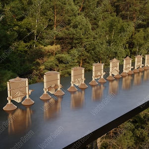 May include: A set of 10 wooden kinetic sculptures, each with a unique design and movement. The sculptures are arranged in a row on a wooden table, with a blurred background of green trees.