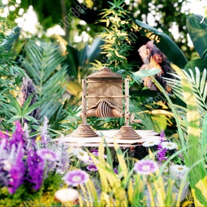 May include: A wooden kinetic sculpture with a complex design, featuring a series of interlocking pieces that move in a rhythmic pattern. The sculpture is placed on a tree stump in a lush green garden setting.