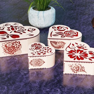 Pode incluir: Quatro caixas de madeira em forma de cora&ccedil;&atilde;o com intrincados desenhos florais vermelhos. As caixas s&atilde;o feitas de madeira clara e t&ecirc;m um acabamento natural.