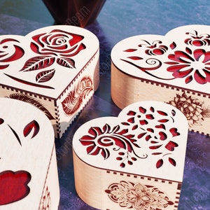 Pode incluir: Quatro caixas de madeira em forma de cora&ccedil;&atilde;o com intrincados desenhos florais vermelhos recortados. As caixas est&atilde;o dispostas em semic&iacute;rculo sobre uma superf&iacute;cie roxa.