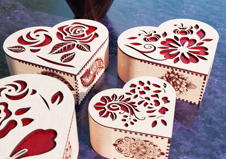 Pode incluir: Quatro caixas de madeira em forma de cora&ccedil;&atilde;o com intrincados desenhos florais vermelhos recortados. As caixas est&atilde;o dispostas em semic&iacute;rculo sobre uma superf&iacute;cie roxa.