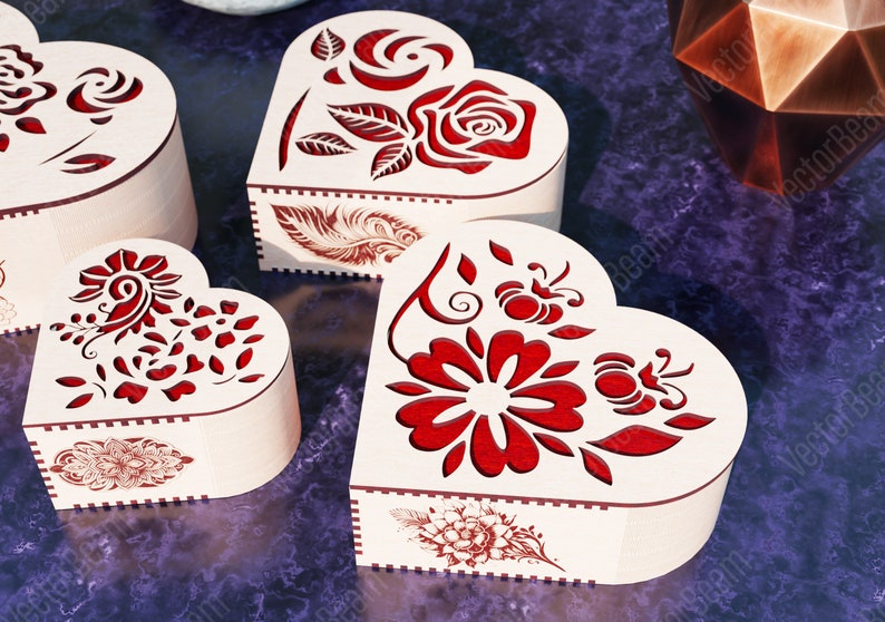 Pode incluir: Quatro caixas de madeira em forma de cora&ccedil;&atilde;o com intrincados desenhos florais vermelhos. As caixas s&atilde;o feitas de madeira clara e t&ecirc;m um aspeto delicado e artesanal.